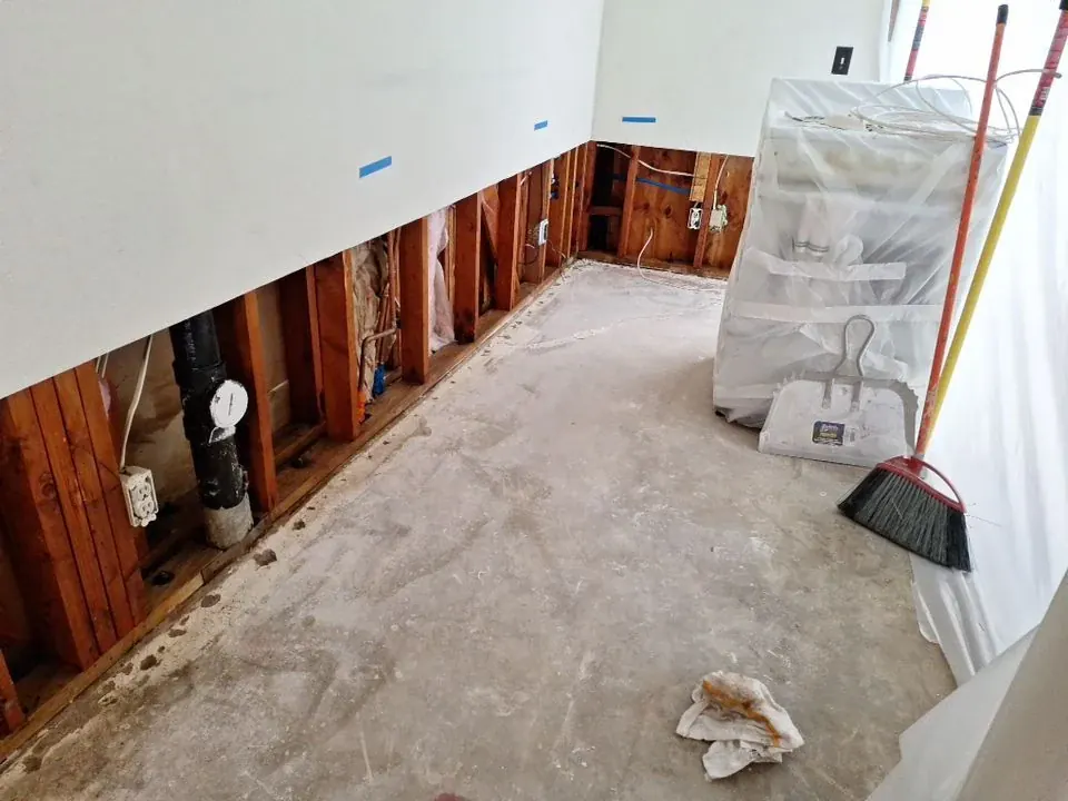 Kitchen flood cuts exposing wall studs during water damage restoration and insurance documentation